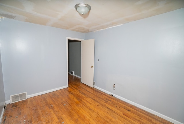 unfurnished room with hardwood / wood-style flooring, baseboards, and visible vents