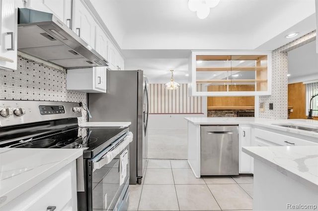 kitchen with light tile patterned flooring, a sink, white cabinetry, wall chimney range hood, and appliances with stainless steel finishes