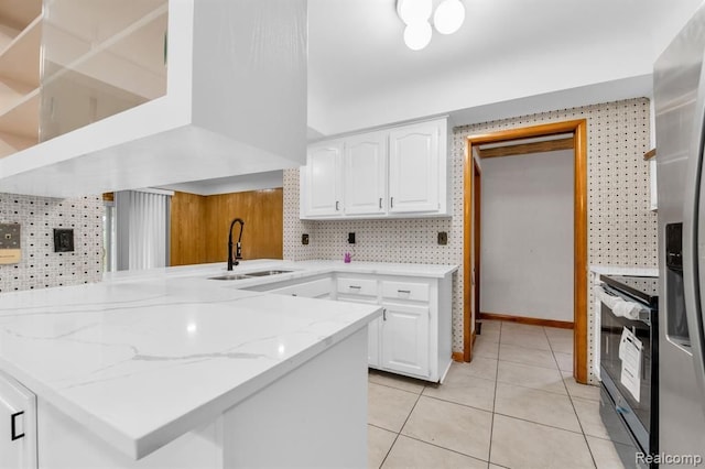 kitchen with electric range oven, white cabinets, a sink, light stone countertops, and a peninsula