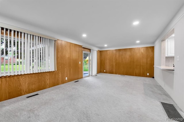 empty room featuring wood walls, carpet, and visible vents