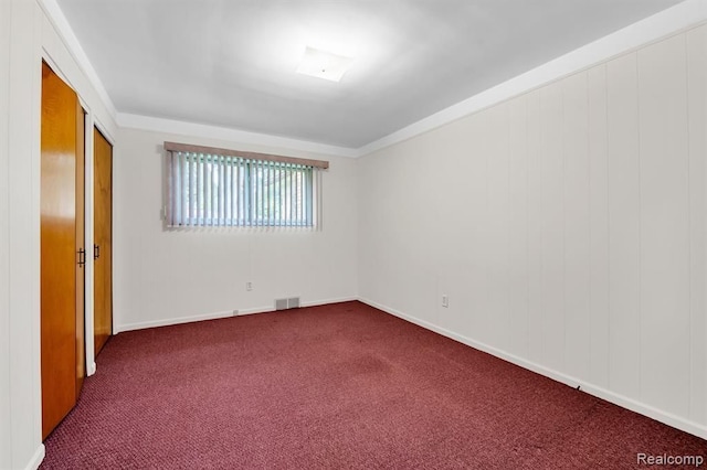 empty room featuring dark colored carpet and visible vents