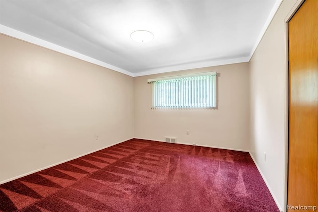 carpeted spare room featuring visible vents, ornamental molding, and baseboards