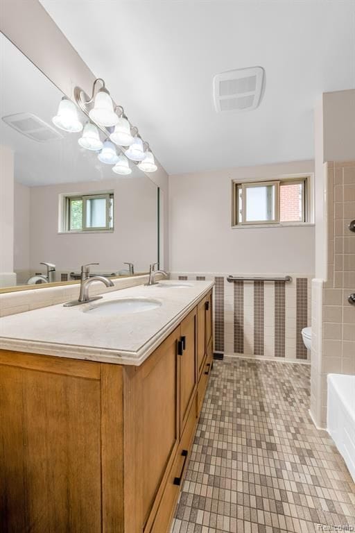 bathroom featuring a wealth of natural light, a sink, toilet, and double vanity