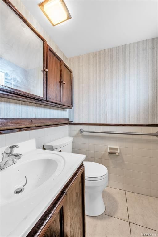 bathroom featuring wallpapered walls, toilet, a wainscoted wall, tile patterned flooring, and vanity