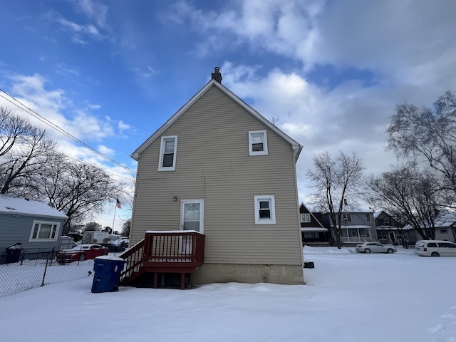 snow covered property featuring a chimney and fence