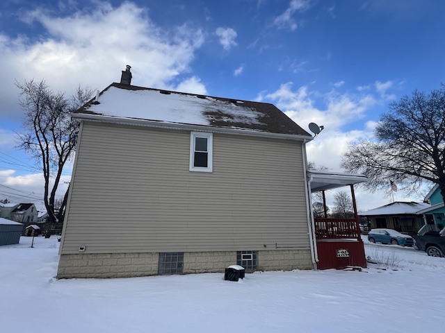 view of snowy exterior with a chimney