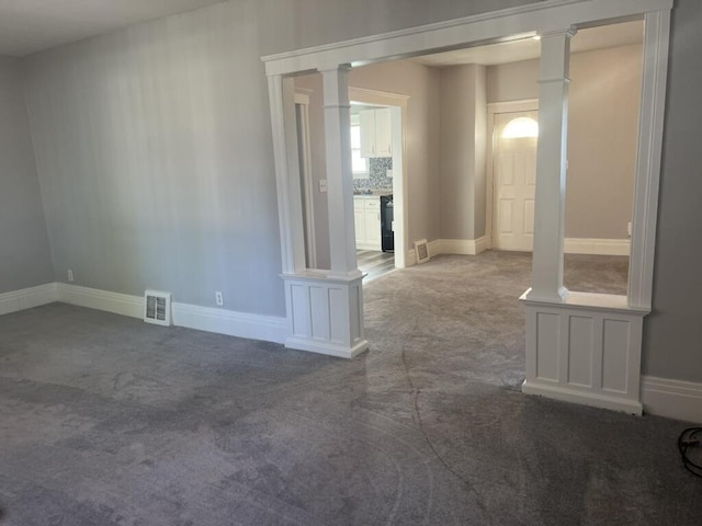 carpeted empty room with baseboards, visible vents, and ornate columns