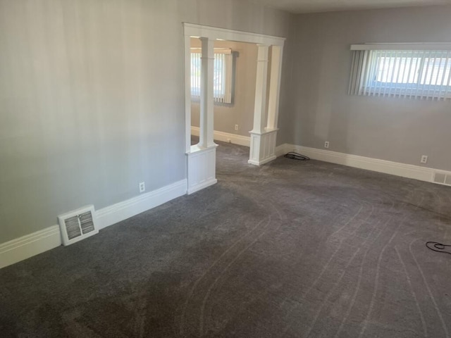 empty room with decorative columns, visible vents, and baseboards