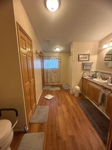 bathroom with toilet, wood finished floors, visible vents, vanity, and baseboards