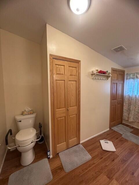 bathroom featuring baseboards, visible vents, lofted ceiling, toilet, and wood finished floors