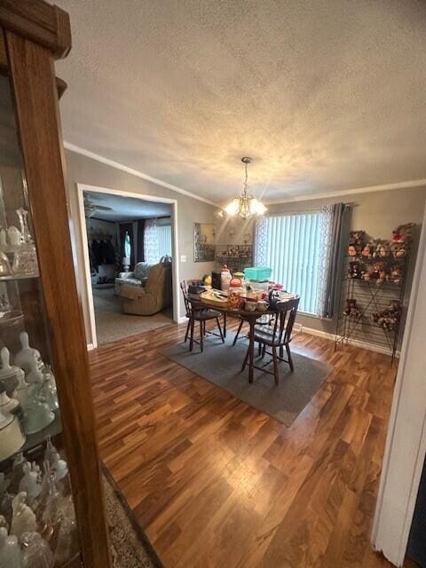 dining area featuring lofted ceiling, a textured ceiling, wood finished floors, and crown molding