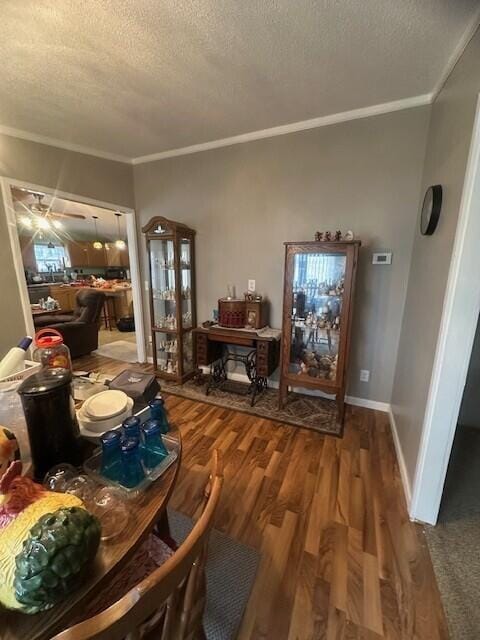 interior space with crown molding, a ceiling fan, a textured ceiling, wood finished floors, and baseboards