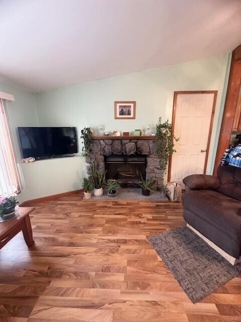 living area with vaulted ceiling, a fireplace, and wood finished floors