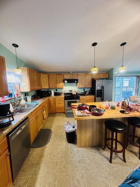 kitchen featuring dishwashing machine, fridge with ice dispenser, stainless steel stove, under cabinet range hood, and a sink