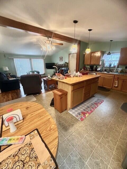 kitchen with pendant lighting, open floor plan, plenty of natural light, and lofted ceiling with beams