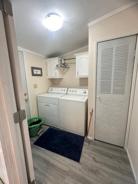 laundry room featuring light wood-type flooring, ornamental molding, independent washer and dryer, and cabinet space