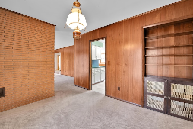 carpeted empty room featuring brick wall and wooden walls