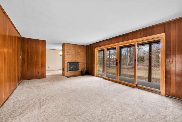 unfurnished living room with light carpet, a fireplace, and wood walls