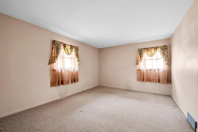 carpeted empty room with baseboards, visible vents, and a healthy amount of sunlight