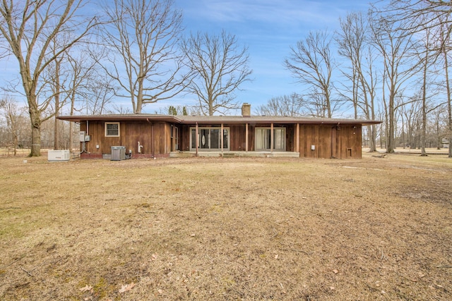 ranch-style house featuring board and batten siding, a chimney, and a front lawn