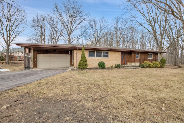 single story home featuring aphalt driveway, brick siding, an attached garage, and a front lawn