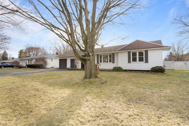 ranch-style house featuring driveway, an attached garage, fence, and a front yard