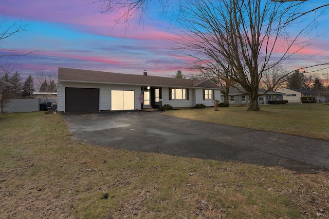 view of front of house featuring driveway, a garage, central AC unit, fence, and a front yard