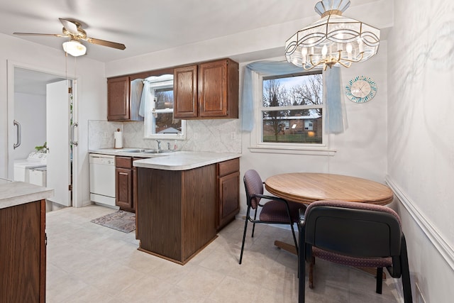 kitchen with washer and clothes dryer, dishwasher, backsplash, light countertops, and a sink