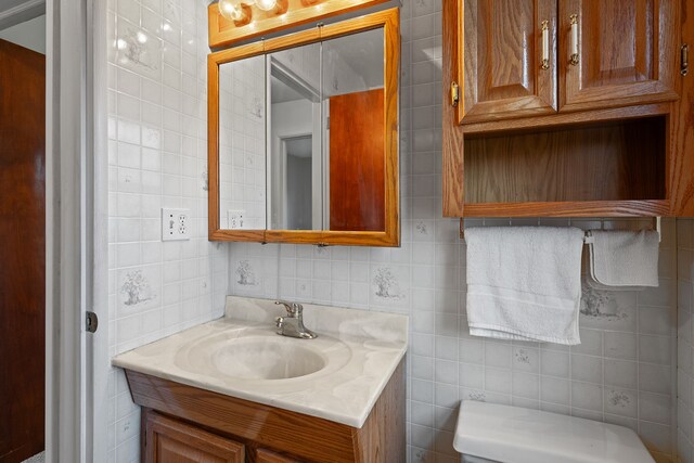 bathroom featuring toilet, tile walls, and vanity