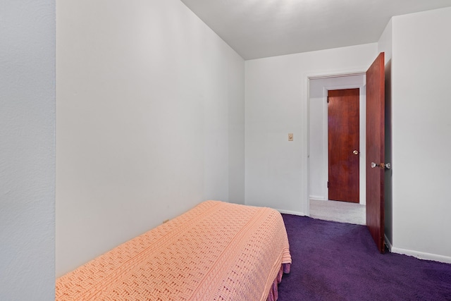 bedroom featuring dark colored carpet and baseboards