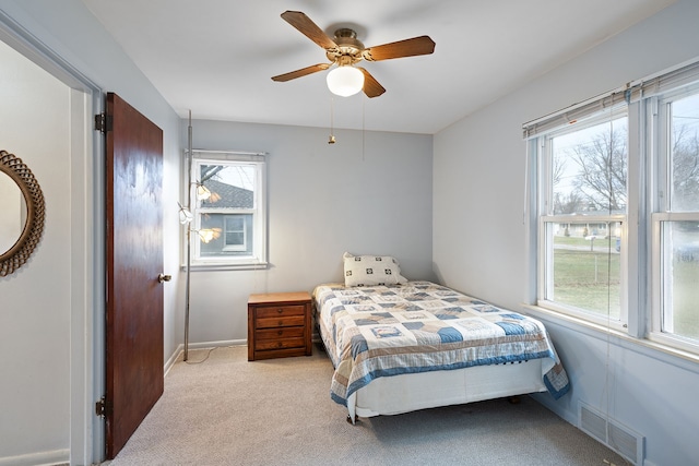 bedroom with baseboards, a ceiling fan, visible vents, and light colored carpet