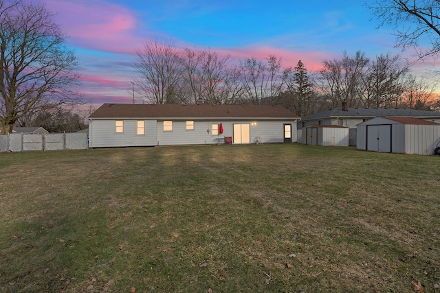 back of house with an outbuilding, a yard, fence, and a storage unit