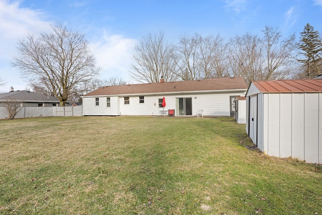 rear view of house featuring a storage shed, an outdoor structure, fence, a yard, and a chimney