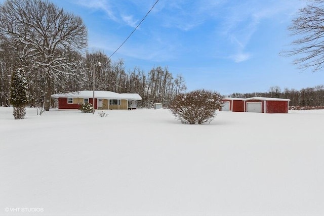 snowy yard featuring a garage and an outdoor structure