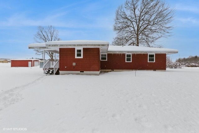 snow covered back of property featuring crawl space