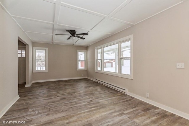 unfurnished room featuring a healthy amount of sunlight, baseboard heating, and wood finished floors