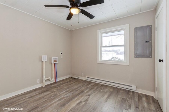 unfurnished room featuring a baseboard heating unit, wood finished floors, electric panel, and baseboards