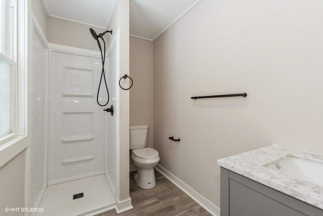 bathroom with toilet, a stall shower, wood finished floors, and vanity