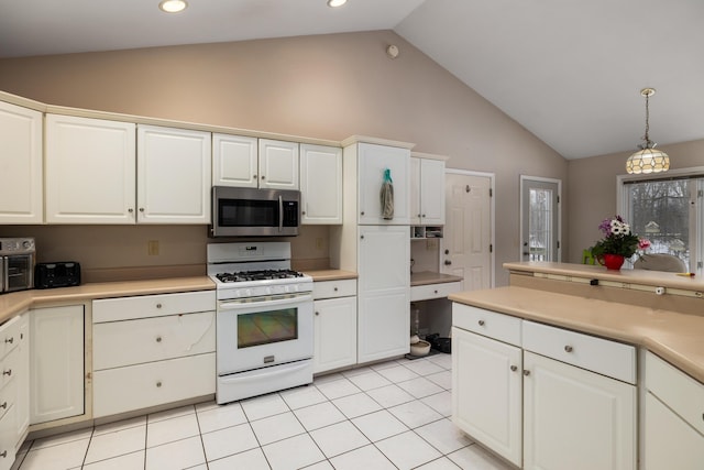 kitchen with white gas stove, light tile patterned floors, light countertops, stainless steel microwave, and white cabinetry