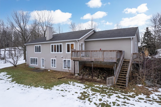 snow covered property featuring roof with shingles, a chimney, stairway, and a wooden deck