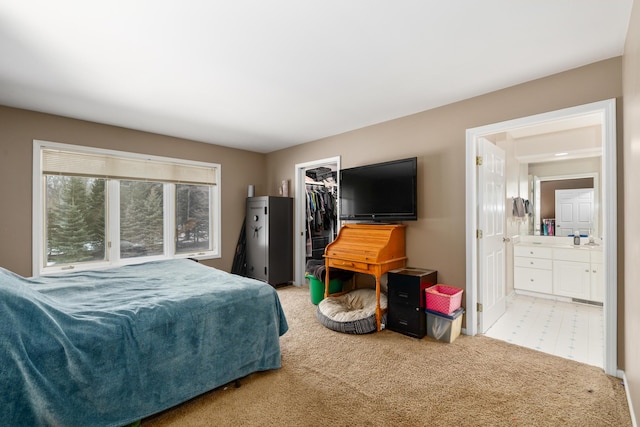 bedroom featuring ensuite bathroom, a closet, a walk in closet, and light colored carpet