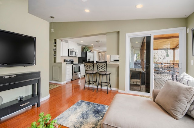 living area with vaulted ceiling, recessed lighting, light wood-type flooring, and baseboards