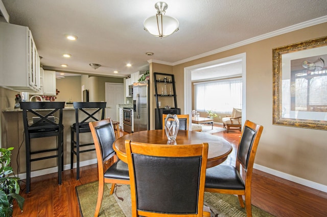 dining area with ornamental molding, a textured ceiling, dark wood finished floors, recessed lighting, and baseboards