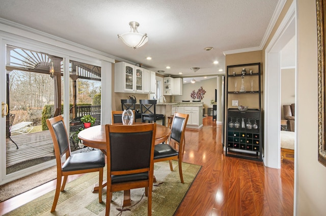 dining space featuring a textured ceiling, recessed lighting, wood finished floors, and ornamental molding