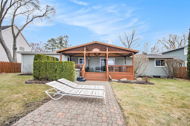 rear view of house with a wooden deck, a lawn, and fence