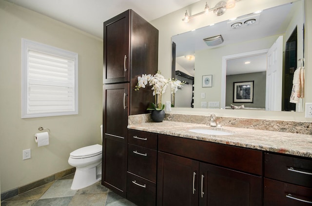 bathroom with toilet, vanity, and baseboards