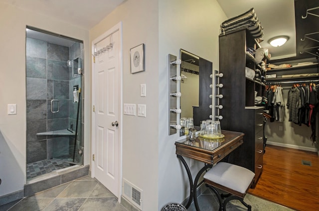 full bathroom with visible vents, baseboards, a spacious closet, and a shower stall