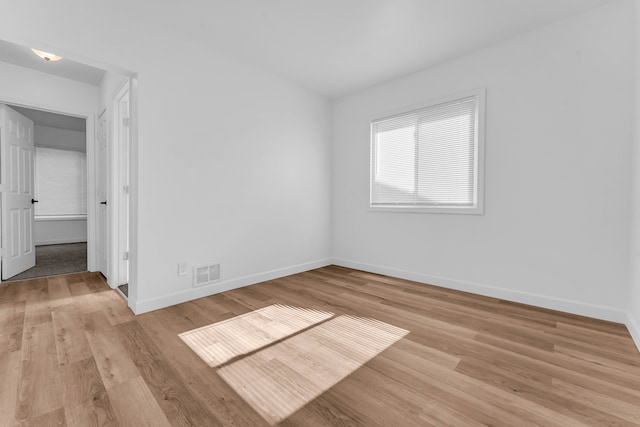 unfurnished room featuring visible vents, light wood-style flooring, and baseboards