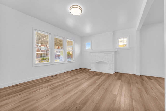 unfurnished living room featuring baseboards, a fireplace, visible vents, and light wood finished floors