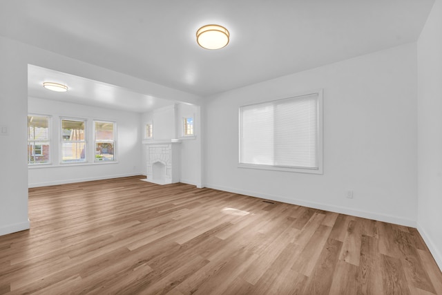 unfurnished living room featuring baseboards, a fireplace, and light wood finished floors